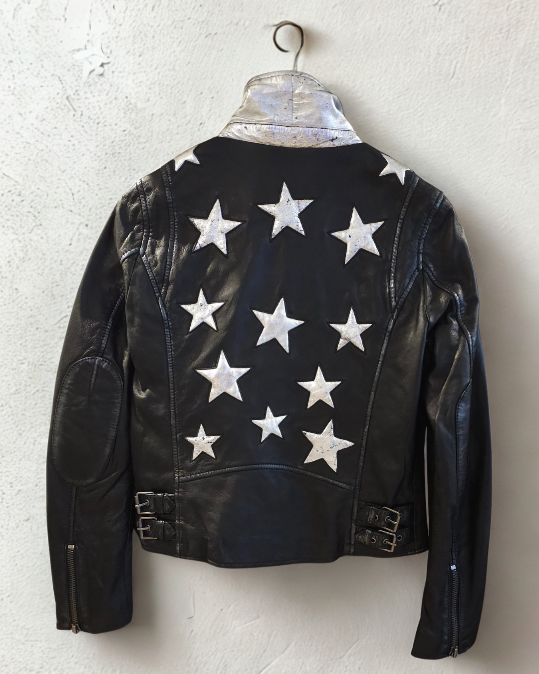 Back view of the Mauritius Christy Black Star Leather Jacket featuring signature silver star appliqués, silver under-collar detail, elbow patches, and distressed lambskin leather.