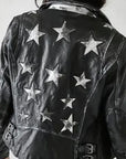 Woman wearing the Mauritius Christy Black Star Leather Jacket in a lifestyle setting, featuring distressed lambskin leather, silver star detailing, and a classic moto silhouette