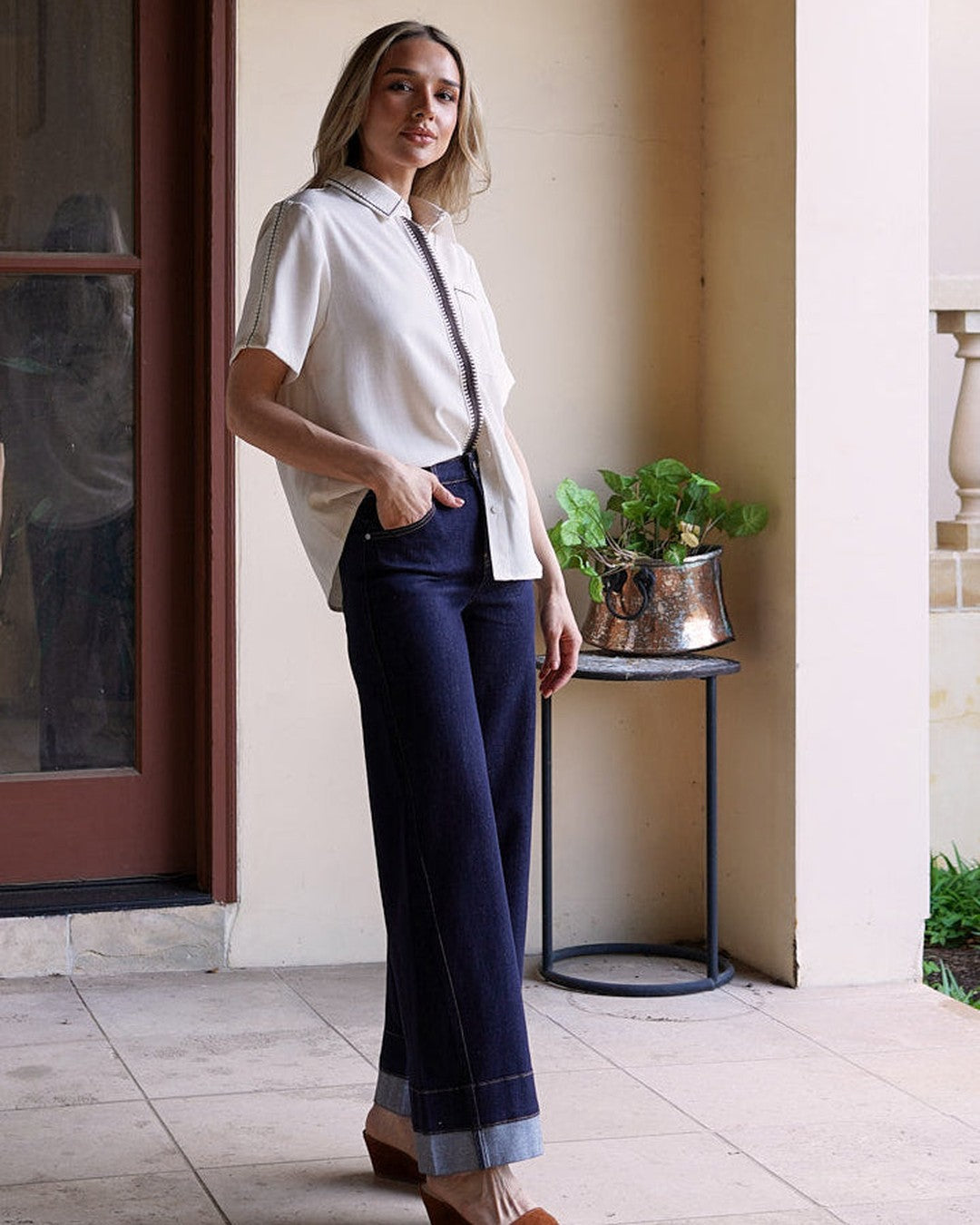 Modern Muse Button Down Blouse in ivory, half-tucked into dark wide leg jeans with brown suede wedge sandals