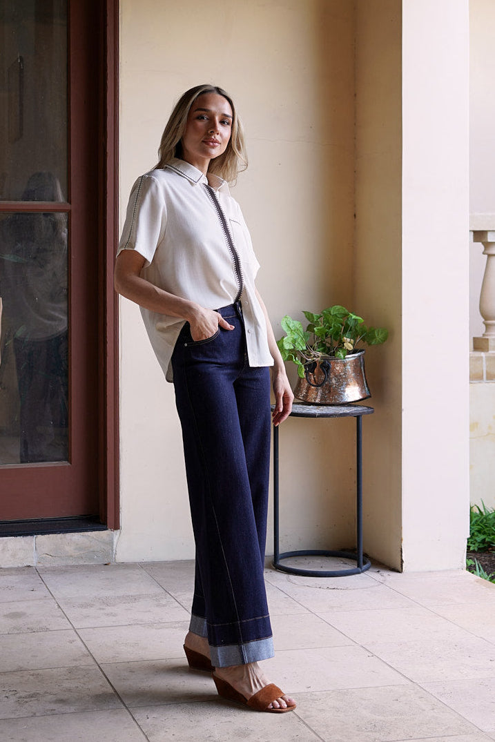 Side view of the Modern Muse Button Down Blouse in ivory featuring contrast trim, short sleeves, and an effortless relaxed fit.