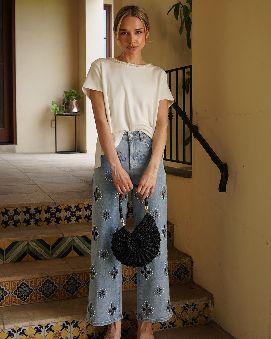 Monaco Pearl Trim Tee with BAYEAS floral pearl jeans, black woven bag and brown wedge sandals on tiled steps