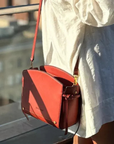 Montemare Roma Crossbody Bag in terracotta worn crossbody with a white dress