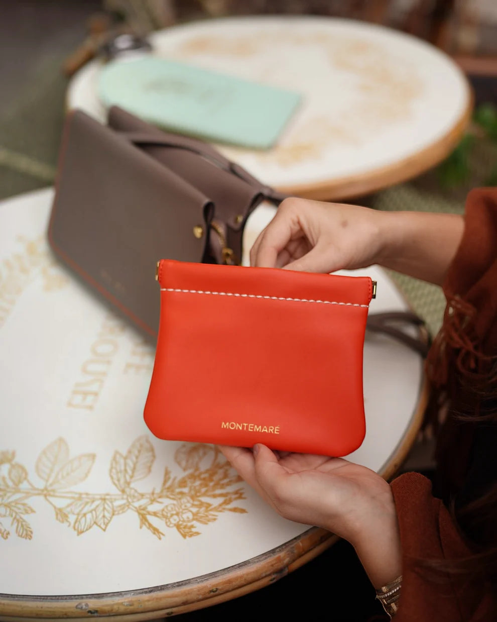 Montemare Roma Square Pouch in Orange shown in a lifestyle setting.