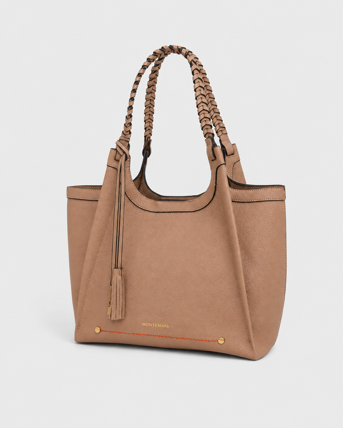 Montemare Sedona Tote in Latte shown from an angled view with braided handles, tassel detail, gold hardware and orange accent stitching.