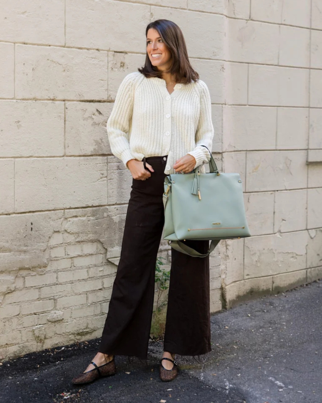 Woman carrying the Montemare Vienna Carry-On in Blake’s Blue with shoulder strap and gold-tone details.
