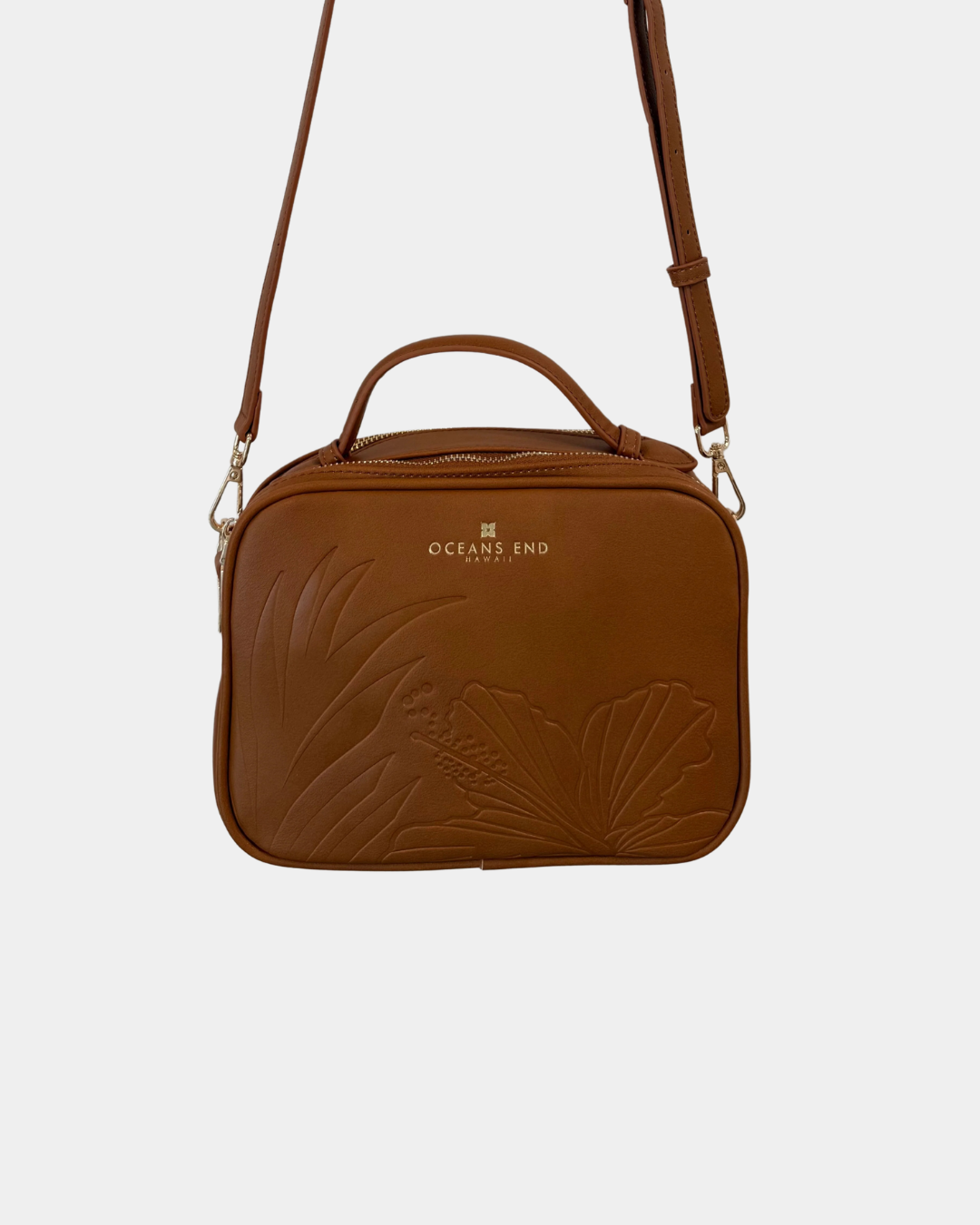 Oceans End Justine 2.0 crossbody bag in saddle featuring an embossed hibiscus design, top handle, adjustable crossbody strap, and gold-tone hardware.