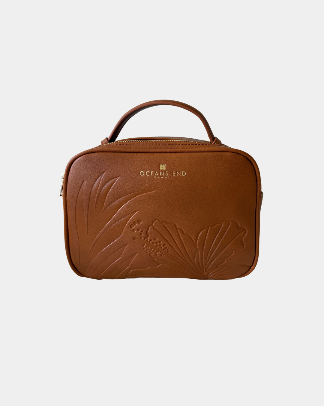 Front view of the Oceans End Justine 2.0 saddle crossbody handbag showcasing the embossed tropical hibiscus artwork and structured silhouette.