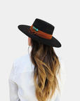The Petra Savage Tasha Boater Crown Hat in black styled on a model for a chic, modern fashion look.