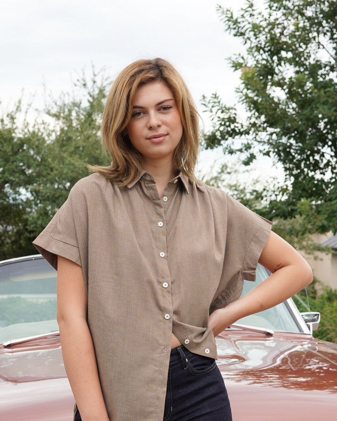 Front view of the mocha Pin Stripe Button Down half-tucked into dark high-rise jeans